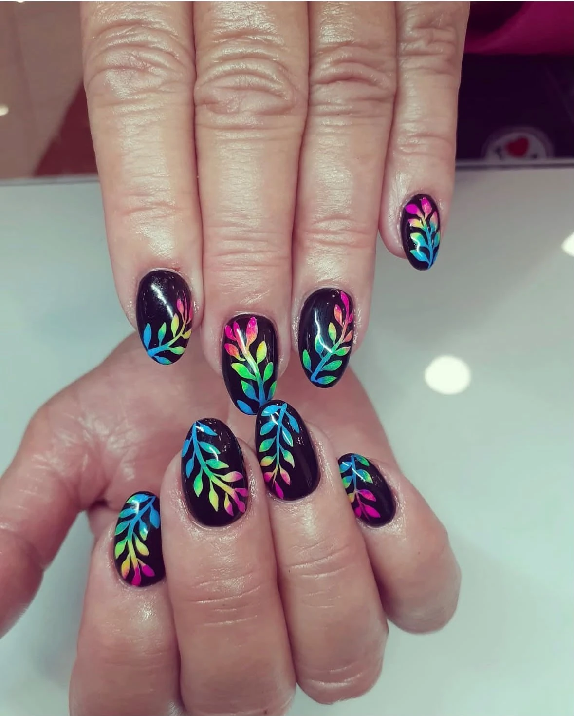 Diseño de uñas negro con hojas multicolor